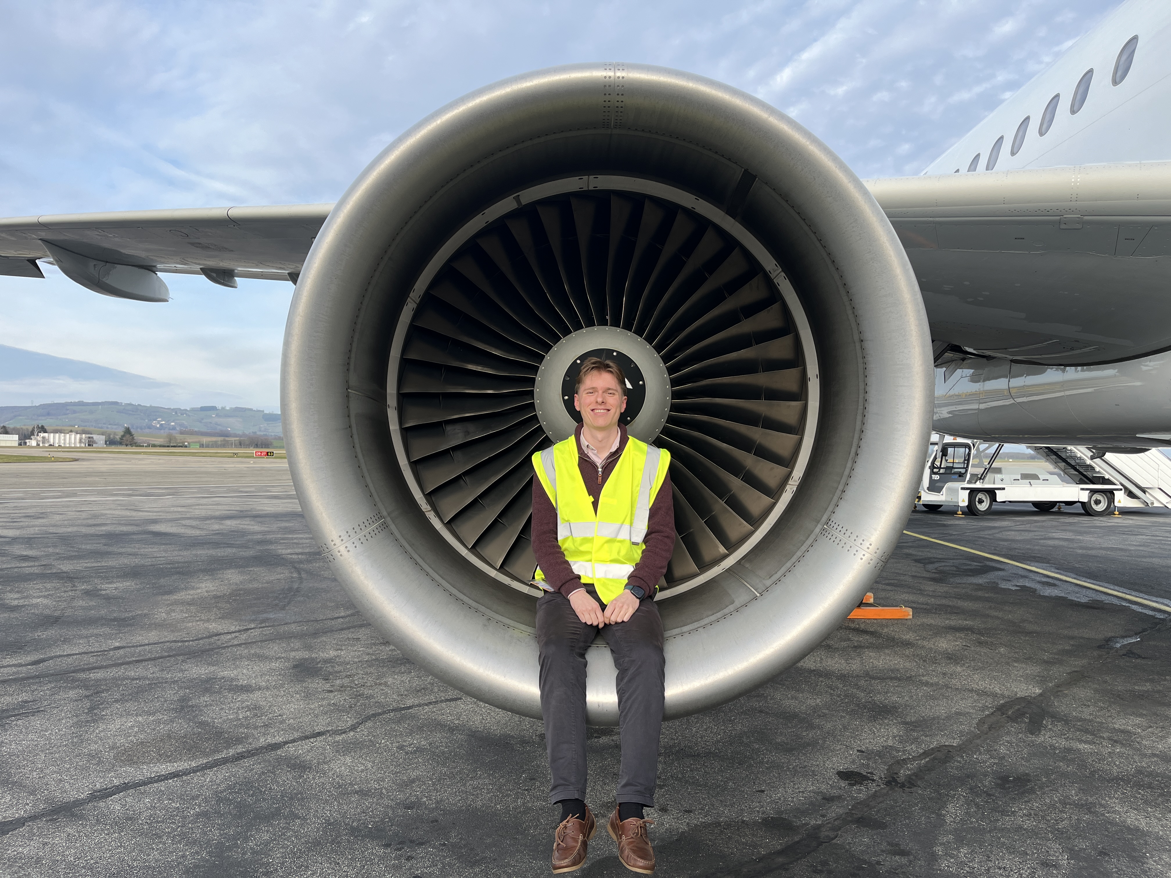 Thomas Haynes seated in front of a large aircraft engine on the ramp